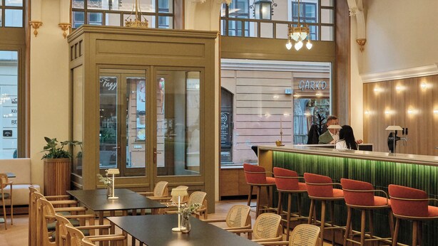 Un ristorante con un lungo tavolo in legno, sedie, una zona bar e un lampadario.