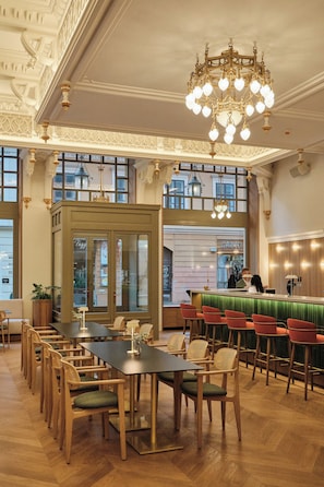 Un restaurante con una larga mesa de madera, sillas, una zona de bar y un candelabro.