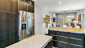 Une cuisine moderne dotée d’un réfrigérateur en acier inoxydable, de meubles de couleur bois foncé et d’un plan de travail en granit.
