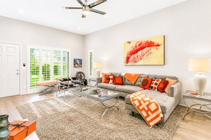 A spacious living room with a sofa, coffee table, and a large painting.