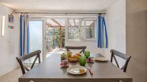 A dining table with chairs, a breakfast setting, and a view through a glass door. - Holiday Home 'Casa Ros' with Sea View, Wi-Fi and Air Conditioning (Palermo)