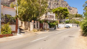 A street with houses, a mountain in the background, and a car parked on the side. - Holiday Home 'Casa Ros' with Sea View, Wi-Fi and Air Conditioning (Palermo)