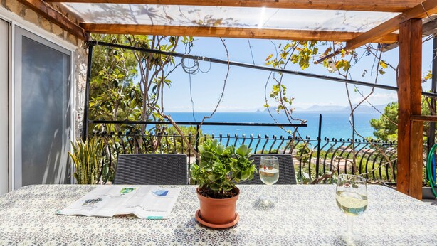 A terrace with a table, a potted plant, and a glass of wine. - Holiday Home 'Casa Ros' with Sea View, Wi-Fi and Air Conditioning (Palermo)