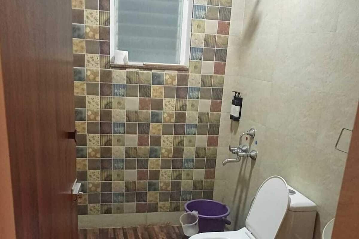 A bathroom with a tiled wall, a window, a toilet, and a shower area.