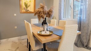 A dining area with a wooden table, white chairs, a bottle of wine, and a menu on a tray.