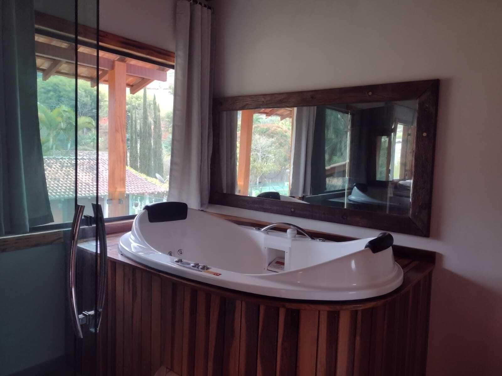 A modern bathroom with a freestanding bathtub, a large mirror, and a view of the outdoors.