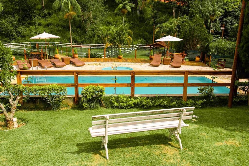 A pool area with lounge chairs, a bench, and umbrellas.