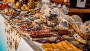 Un buffet con diverse pietanze, tra cui carni, formaggi e frutta.