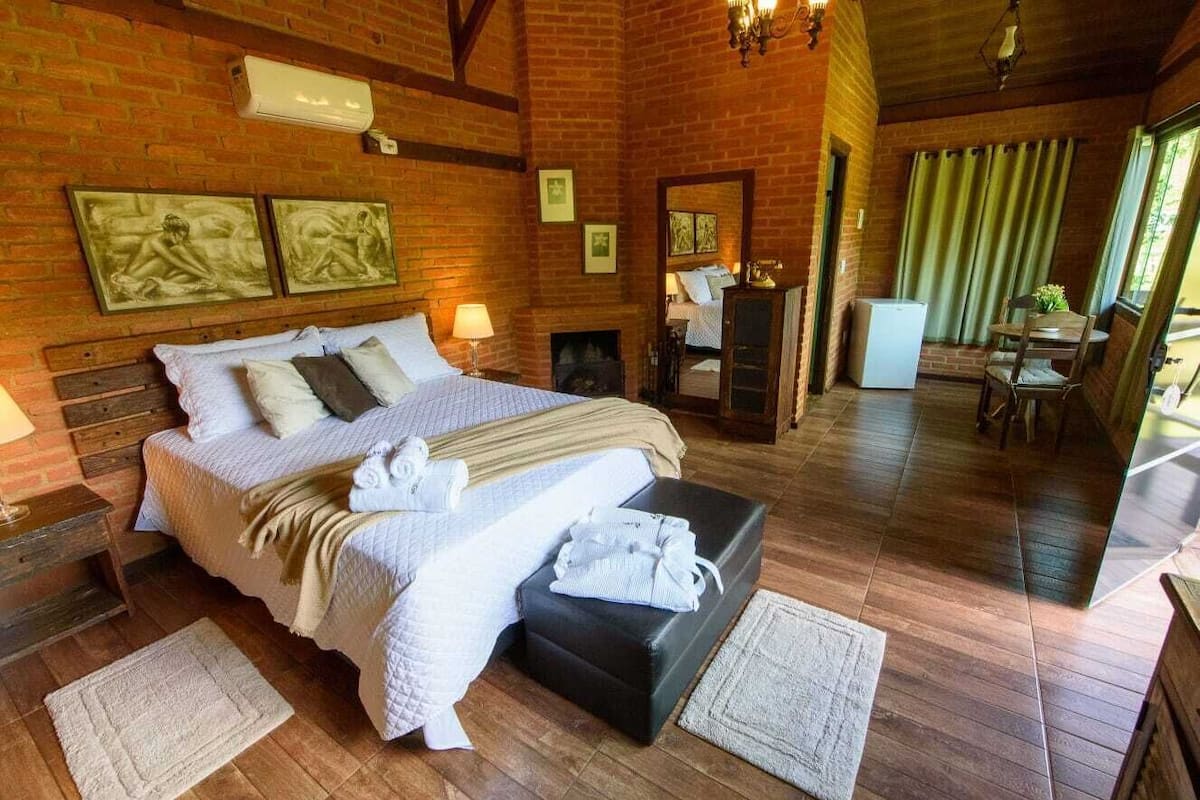 Une chambre confortable avec un grand lit, une cheminée et un coin repas comprenant une table et des chaises.