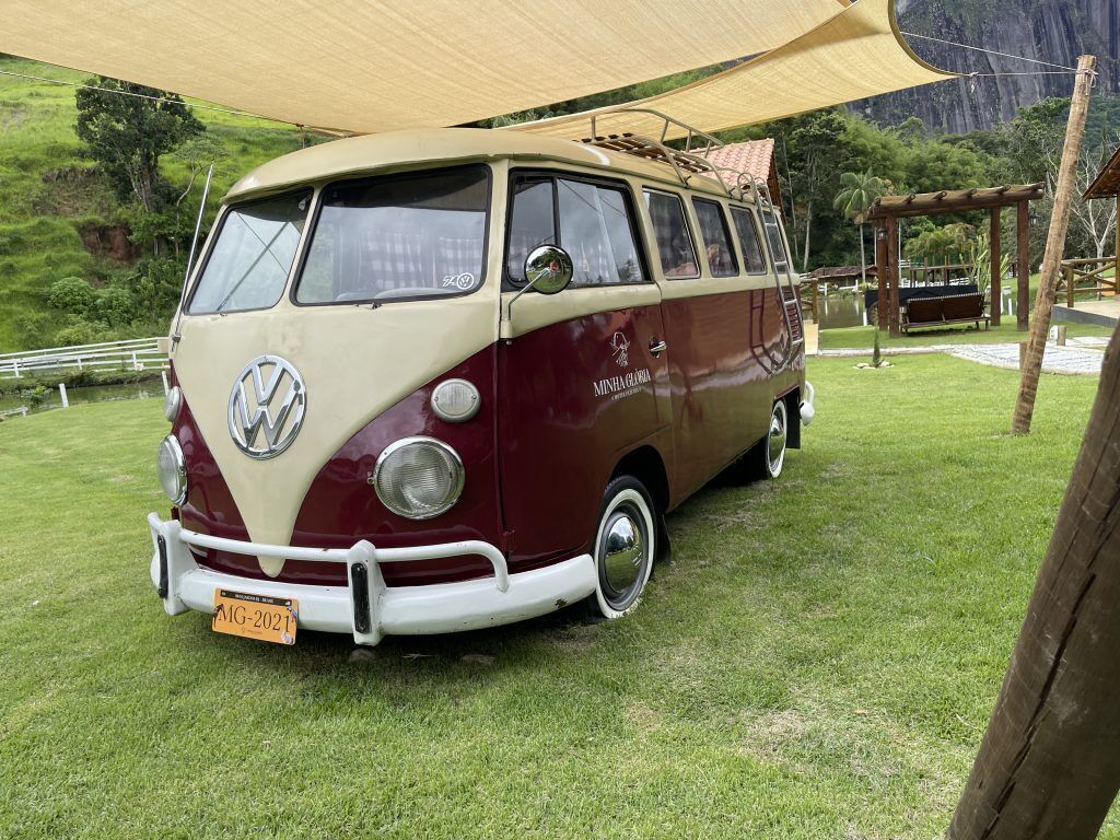 Vanha Volkswagen-pakettiauto on pysäköity nurmikolle, ja sen yläpuolella on katos.