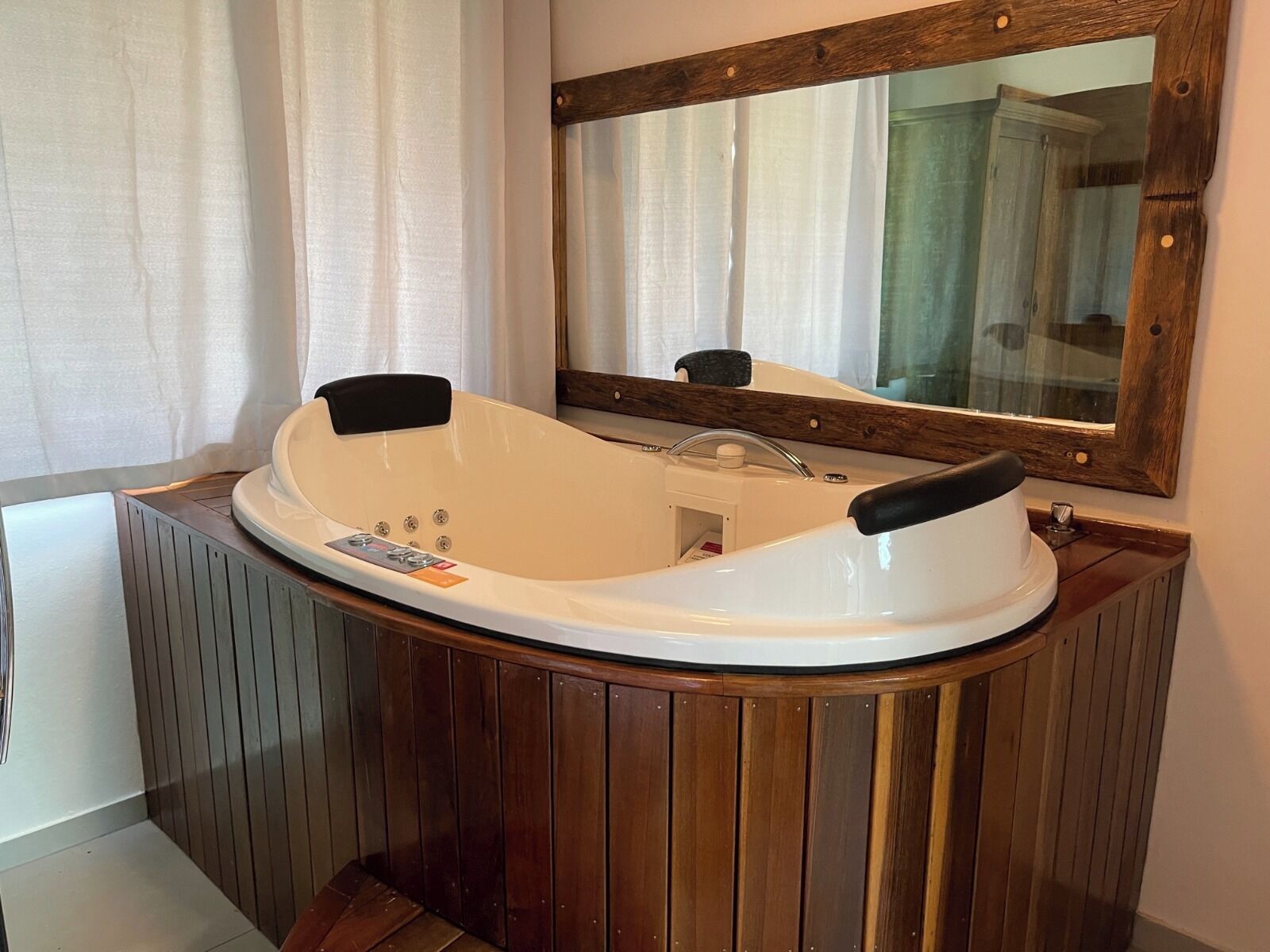 A modern bathroom with a freestanding bathtub, wooden paneling, and a large mirror.