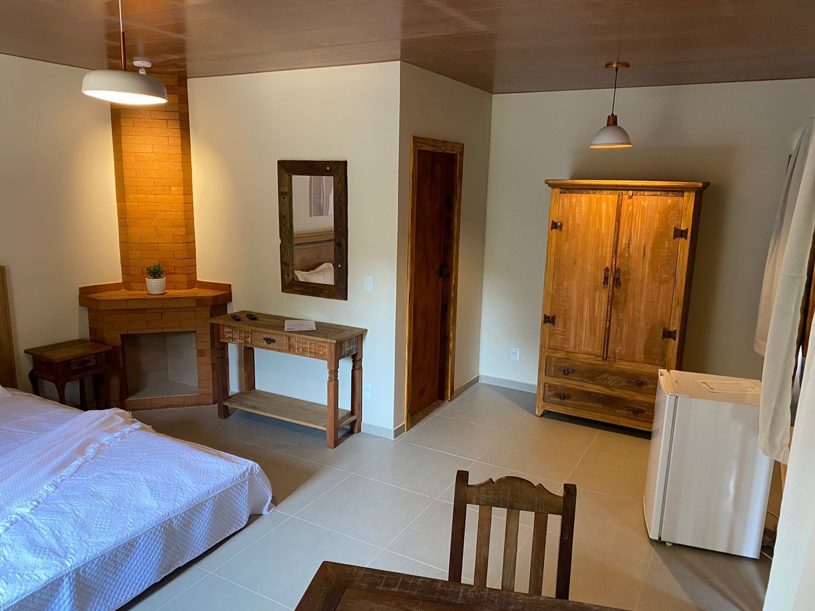 A bedroom with a bed, a wooden desk, a mirror, a wardrobe, and a radiator.
