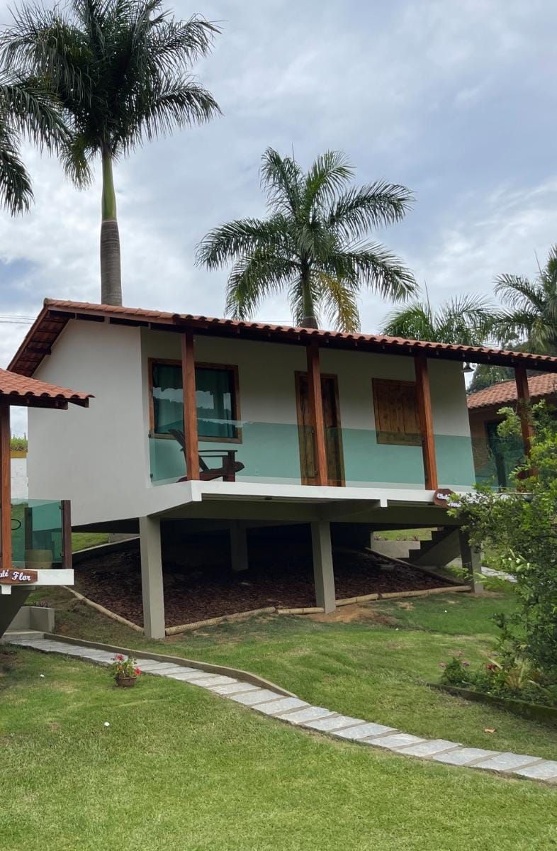 A two-story house with a balcony, surrounded by palm trees and a well-maintained lawn.