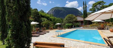 Een buitenzwembad, parasols voor strand/zwembad