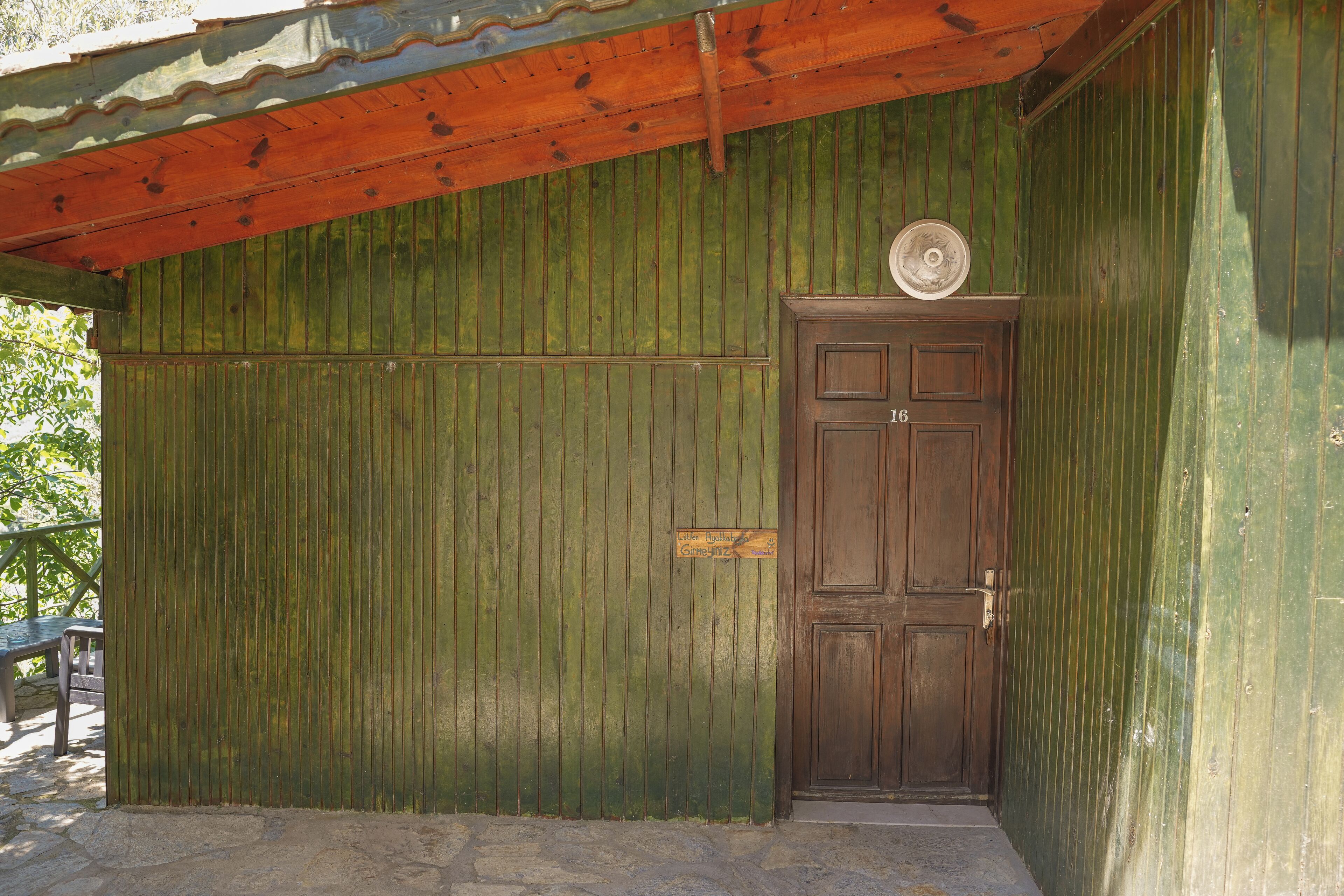 A wooden door with a sign above it, a metal roof, and a stone floor.