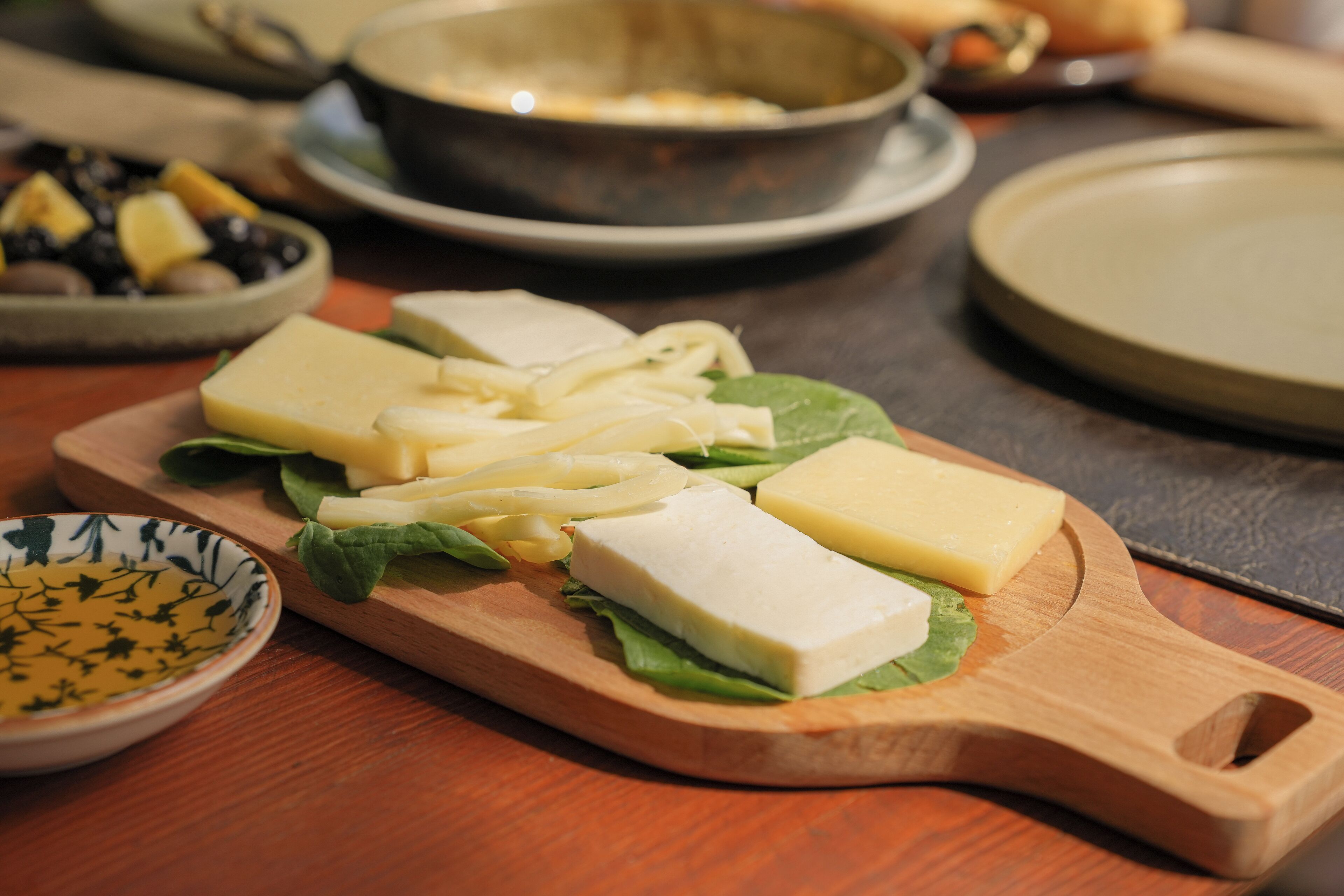 Ein Holzbruchbrett mit Käse und Salat auf einem Tisch.