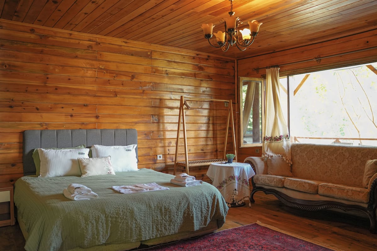 A wooden cabin bedroom with a bed, a sofa, and a table.