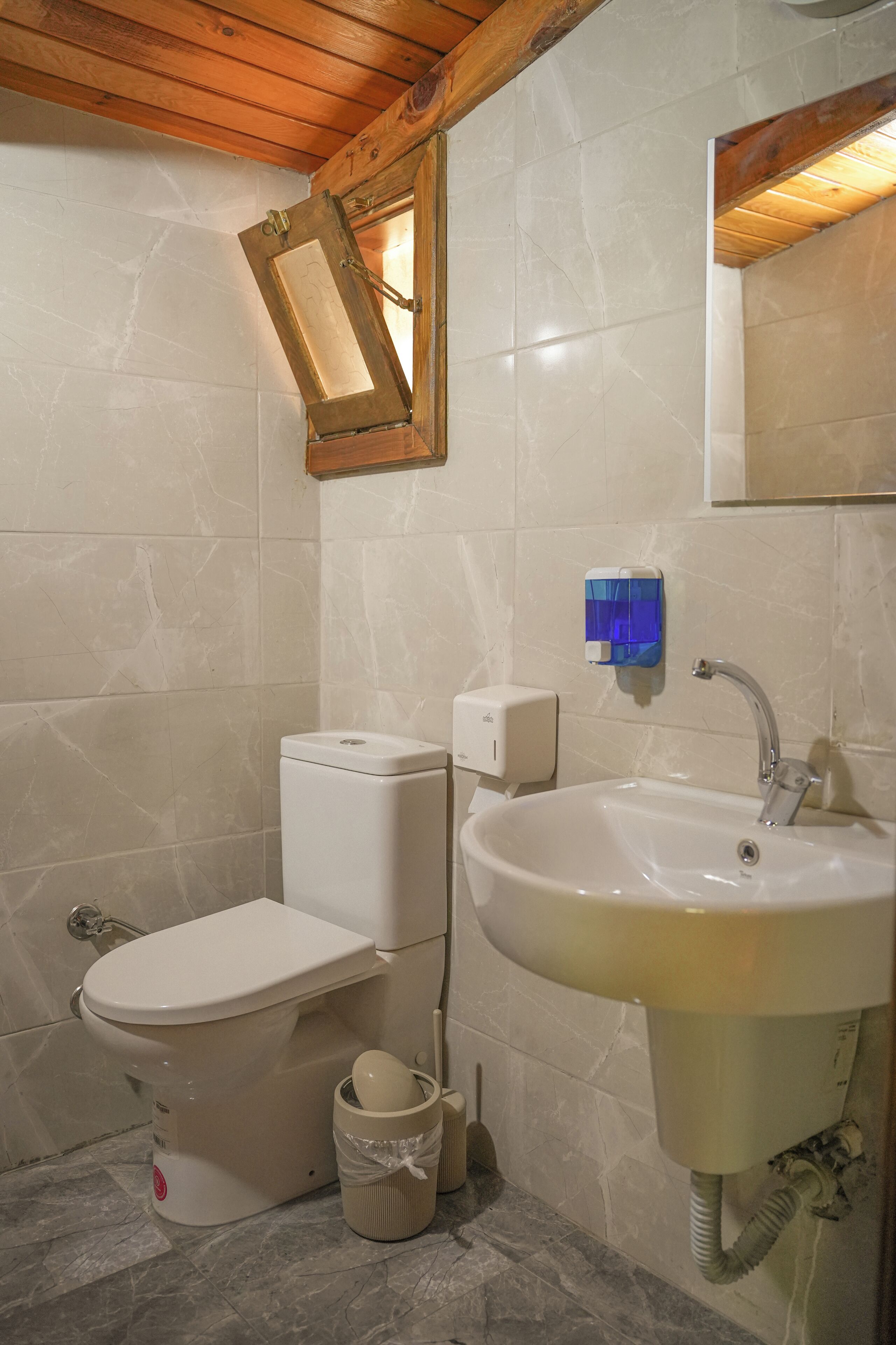 Une salle de bain avec des toilettes, un lavabo et un plafond en bois.