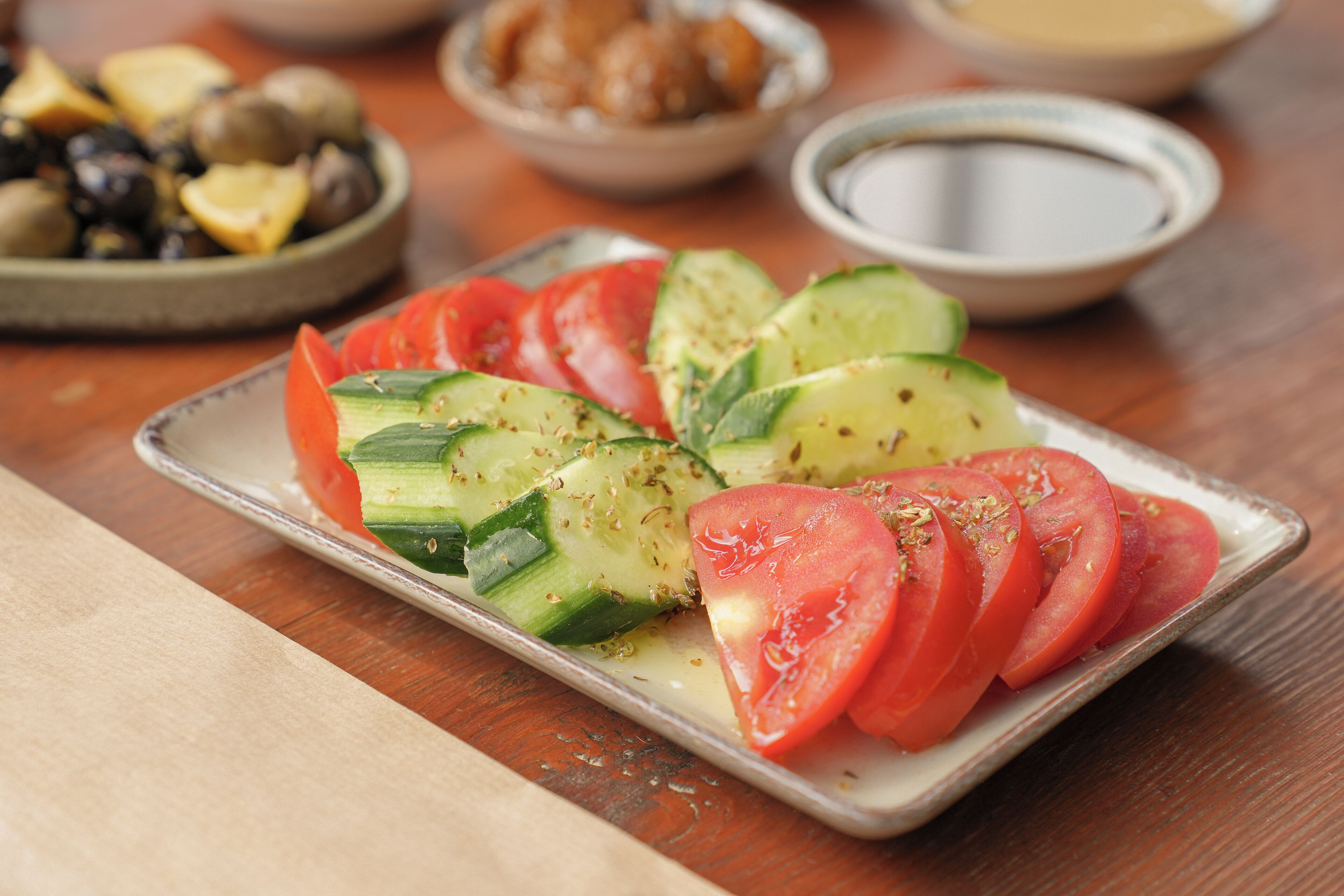 A plate of sliced tomatoes and cucumbers on a tray.