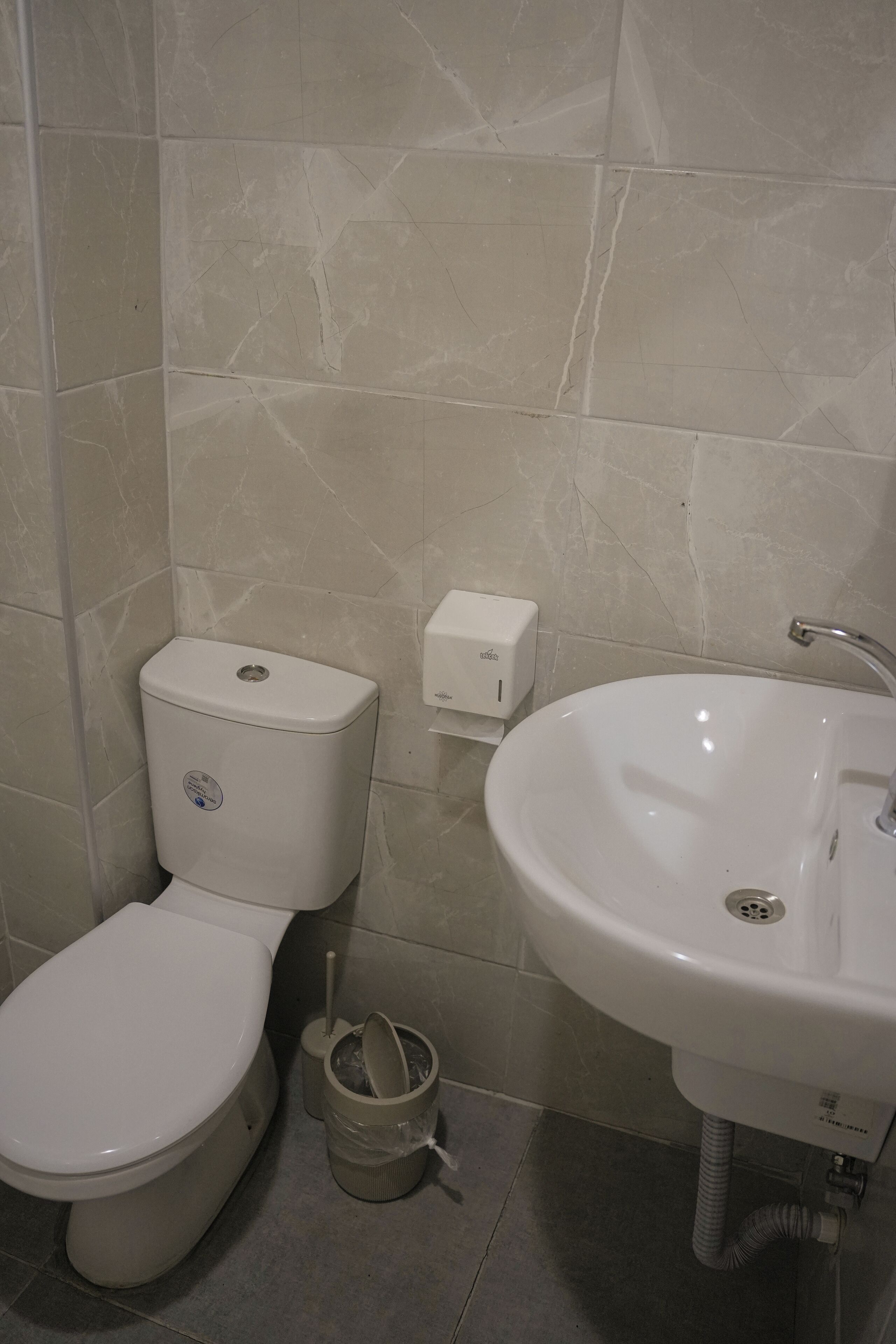 Une salle de bain équipée de toilettes, d’un lavabo et d’une poubelle.