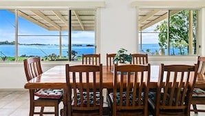 Un comedor con vistas al mar, sillas de madera y una mesa.