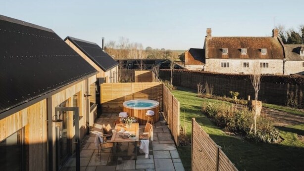 A modern house with a wooden deck, a hot tub, and a patio area. - Longstones Avebury – Adam (Marlborough)
