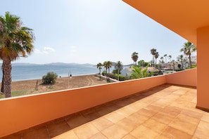 Ein Balkon mit Blick auf das Meer, Palmen und ein fernes Gebirge.