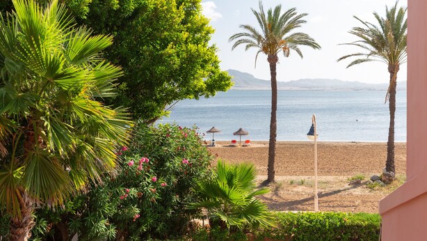 A beach with palm trees, a clear sky, and a view of the sea. - Villa 'La Gola' with Sea Views, Shared Pool and Wi-Fi (La manga)