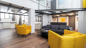 A modern interior with a grey sofa, yellow chairs, a coffee table, and a dining area with a table and chairs. - Italianway Comfort - Mancini 3 (Milan)