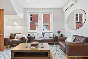 A modern living room with two leather sofas, a wooden coffee table, and a large mirror.