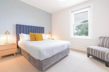 Located upstairs, the primary bedroom offers a queen bed, peaceful treetop views, a portable fan for warmer days, and a wall-panel heater to keep things cosy in cooler months.