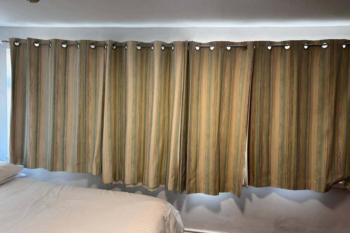 Una habitación de hotel con un ventanal grande, una cama y una cortina con estampado a rayas.