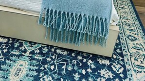 A neatly made bed with a white quilt, blue pillows, and a blue throw blanket. - 3-bedroom condo in charming Melbourne Beach with AC (Melbourne Beach)