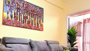 Ein modernes Wohnzimmer mit einem grauen Sofa, einem weißen Couchtisch und einem farbenfrohen, abstrakten Gemälde an der Wand.