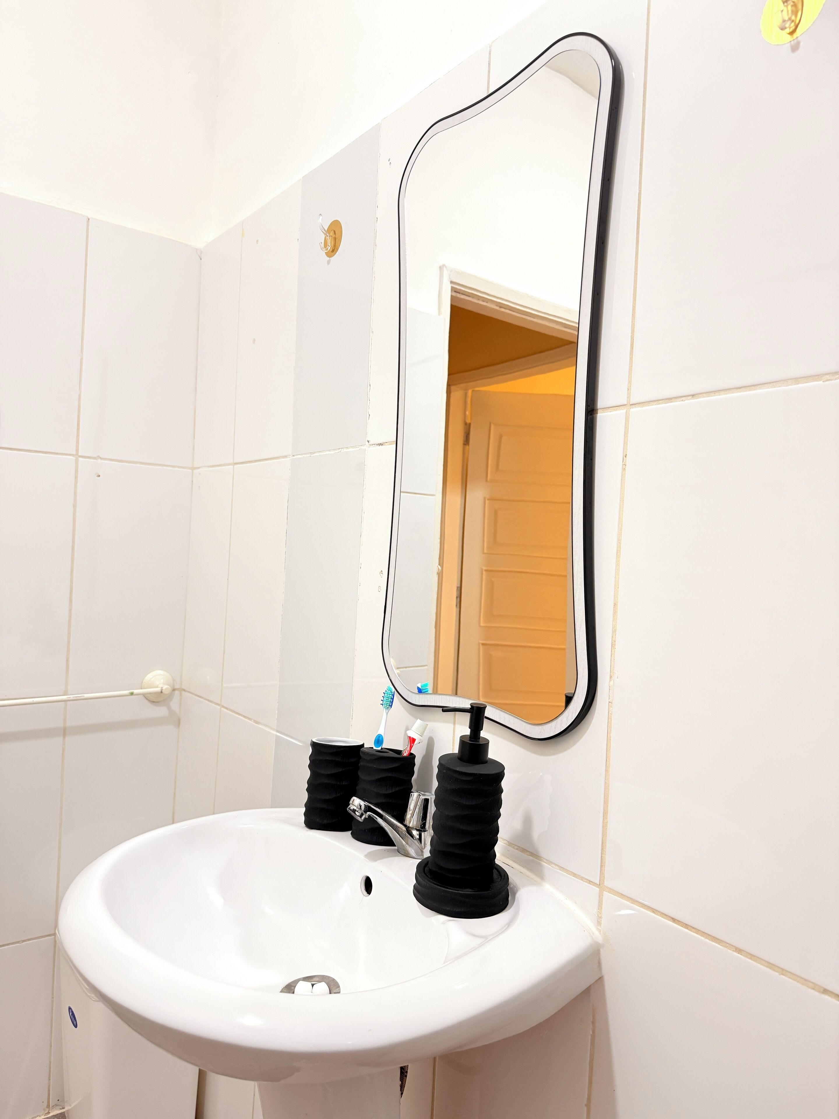 A bathroom with a white sink, a mirror, and a toothbrush holder.