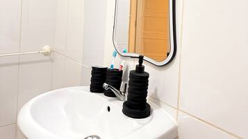 A bathroom with a white sink, a mirror, and a toothbrush holder.