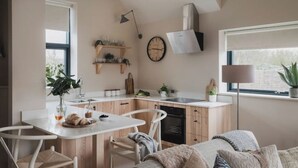 Eine kompakte Küche mit Holzausstattung, einer weißen Arbeitsplatte und einer kleinen Essecke mit Stühlen.