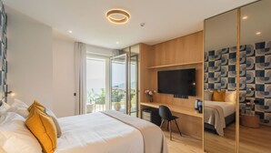 Una habitación de hotel moderna con una cama grande, un escritorio, un televisor de pantalla plana y un balcón accesible mediante una puerta corredera.