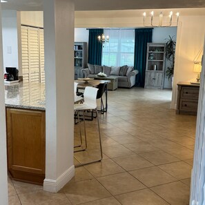 A spacious living area with a dining table, a sofa, and a chandelier.