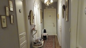 Un pasillo con alfombra estampada, puertas blancas y espejos adheridos a la pared.