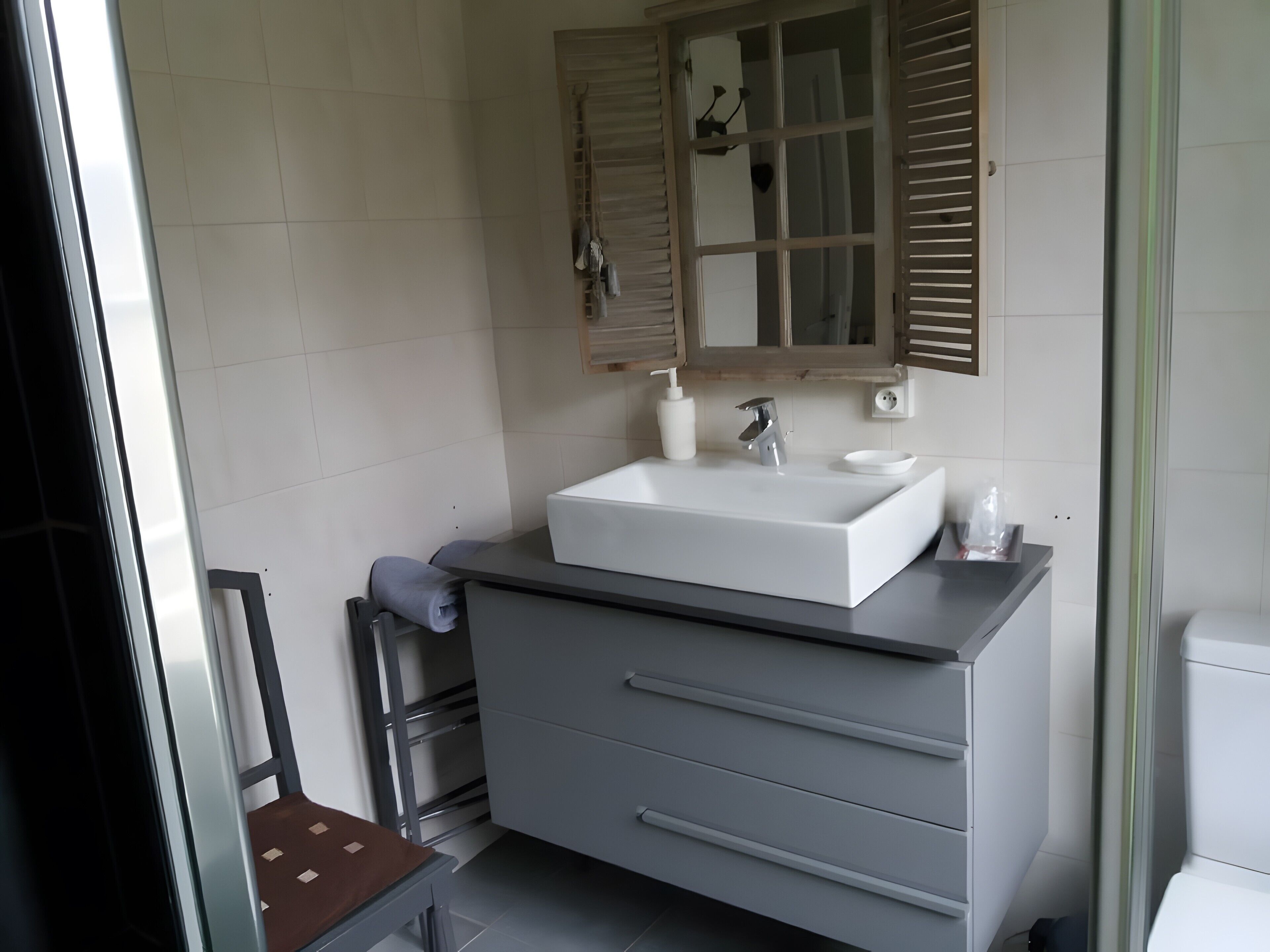 A modern bathroom with a white sink, a mirror, and a towel rack.