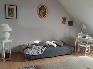 Quarto com cama, cadeira, luminária e um quadro na parede.