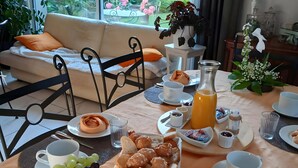 Una mesa de desayuno con frutas, pasteles y vistas a un jardín a través de una ventana.