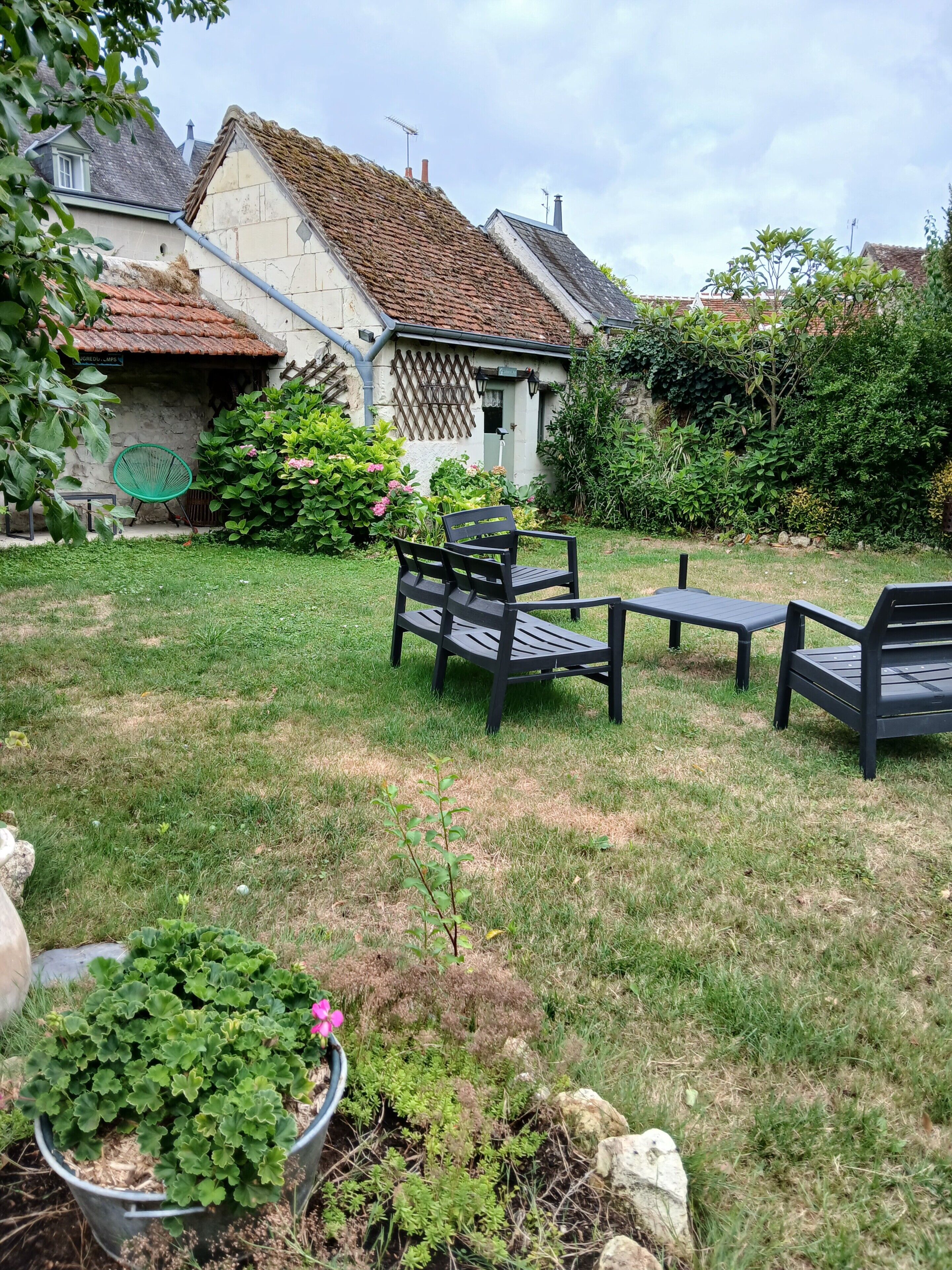 A garden with outdoor furniture, a stone wall, and a building with a tiled roof.