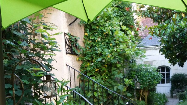 Un espacio al aire libre techado con una escalera, plantas en macetas y un edificio al fondo.