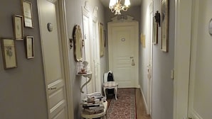 Un couloir avec un tapis à motifs, des portes blanches et des miroirs fixés au mur.