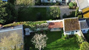 Vue aérienne d’un quartier résidentiel avec un jardin bien entretenu, un petit étang et une variété d’arbres et d’arbustes.