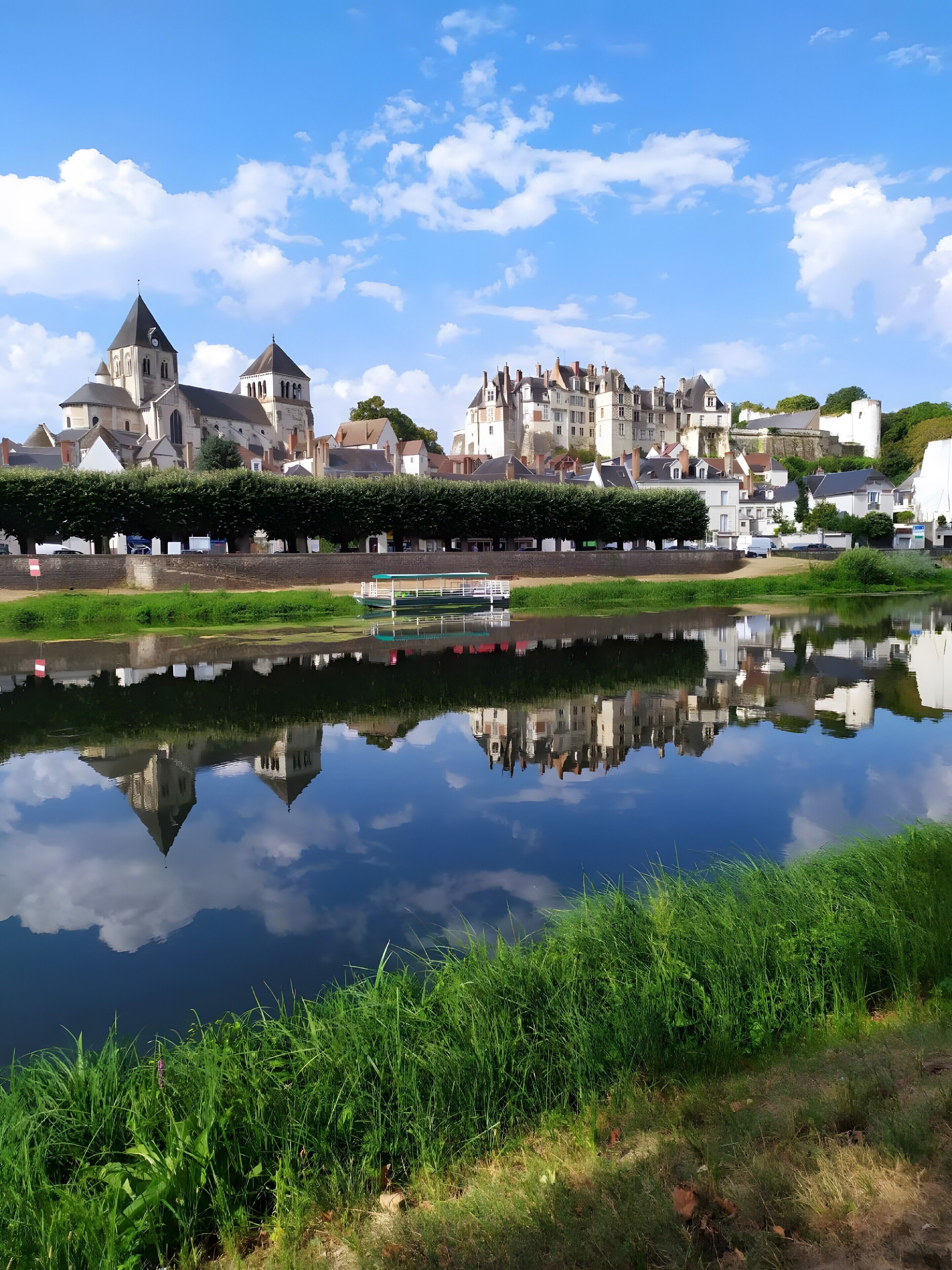 Eine historische Stadt mit einer markanten Kirche, einer Burg und einem ruhigen Fluss, der die Gebäude widerspiegelt.