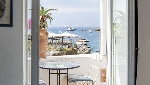 A room with a bed, a table with chairs, and a view of the sea with boats. - Villa Marea by My Villa Collection (Capri)