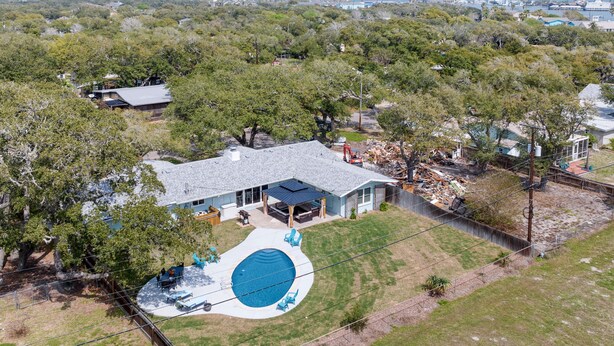 A residential area with a house featuring a large backyard with a swimming pool and patio furniture. - The Sea Glass House | Pet-friendly, Pool (Rockport)